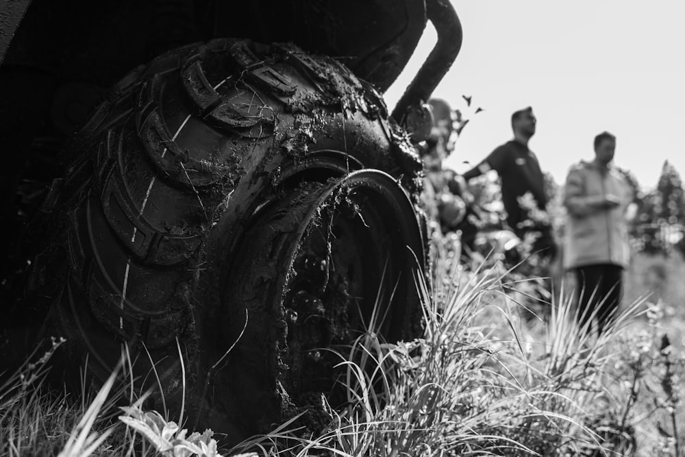 a black and white photo of a group of people looking at a tire