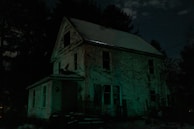 A haunted house with flickering lights and ghostly figures visible in the windows.