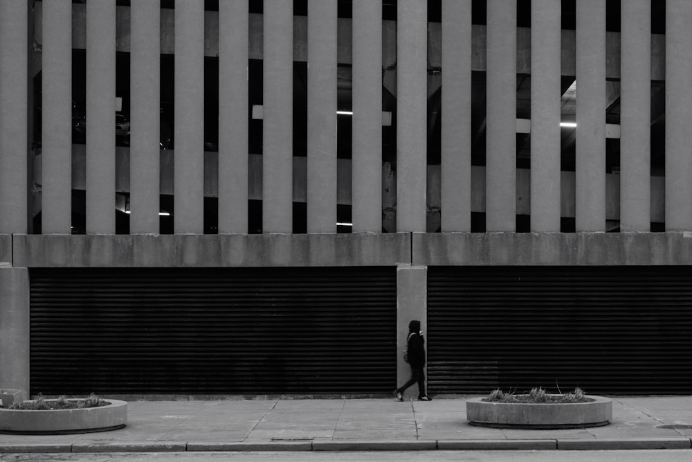 a black and white photo of a person standing in front of a building