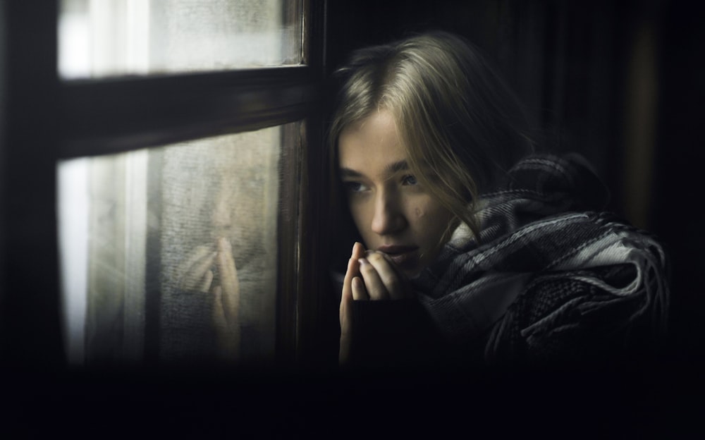 Une femme regarde par une fenêtre
