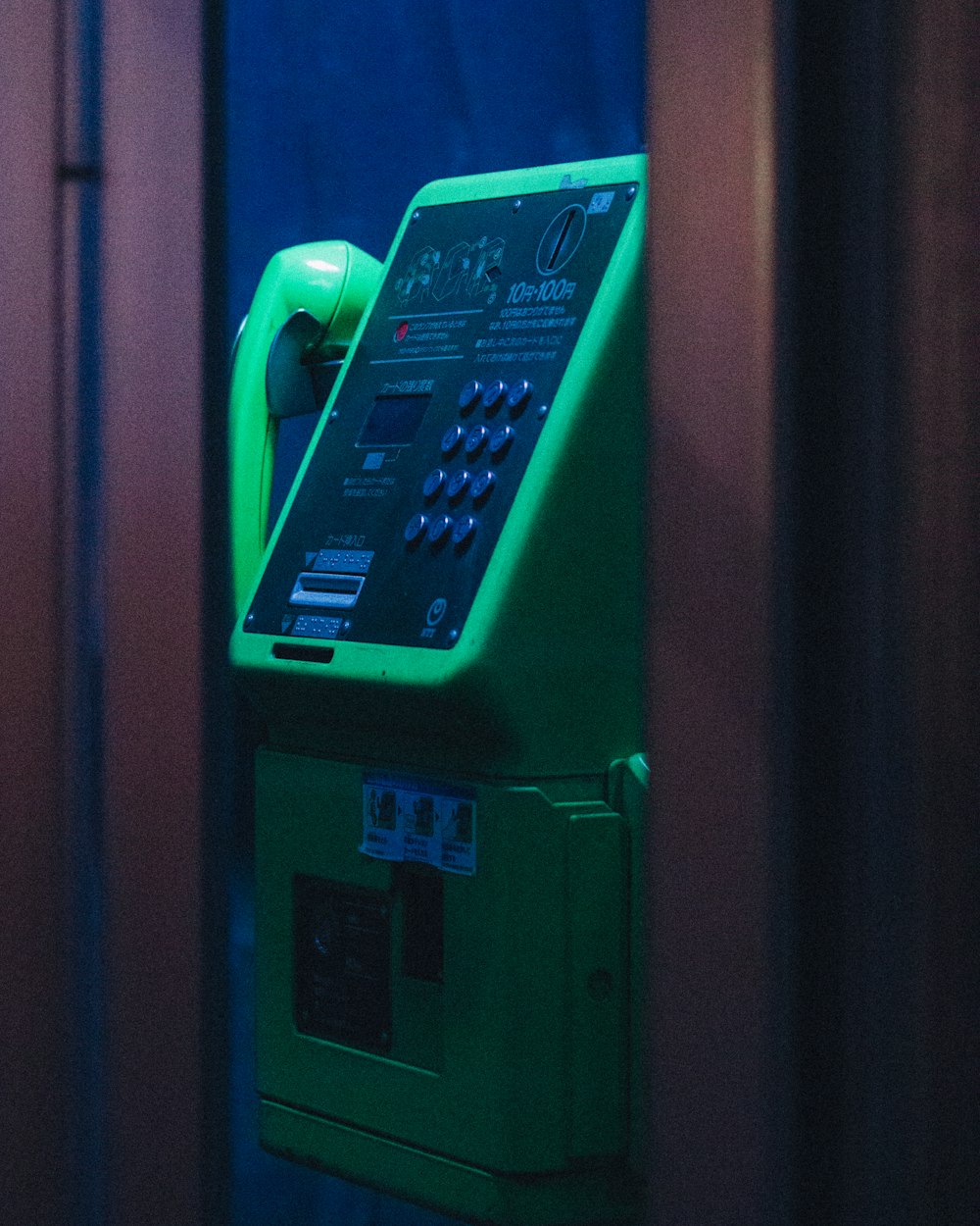 a green pay phone sitting on top of a wall