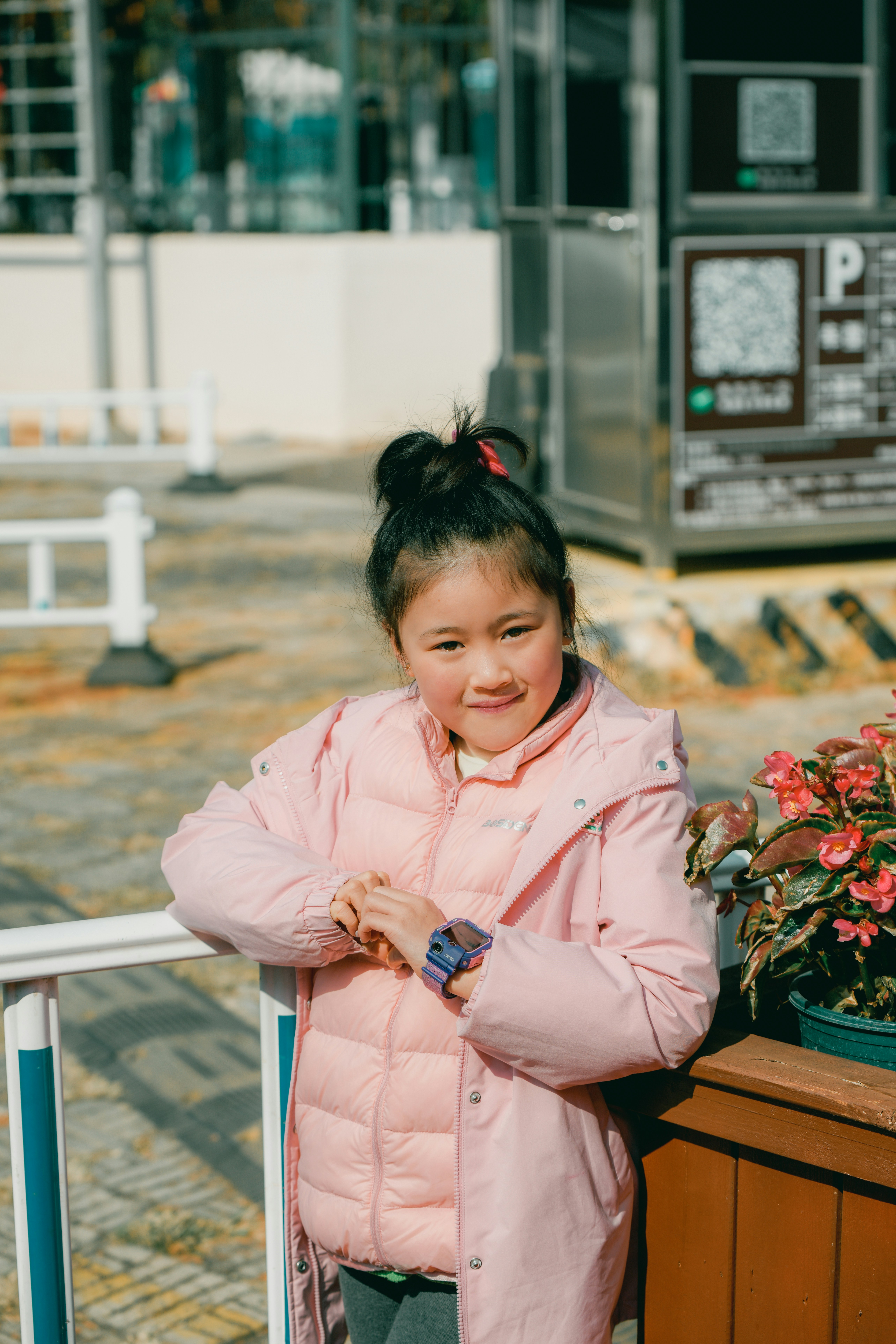 A smiling girl in a pink coat wearing a purple kids smartwatch
