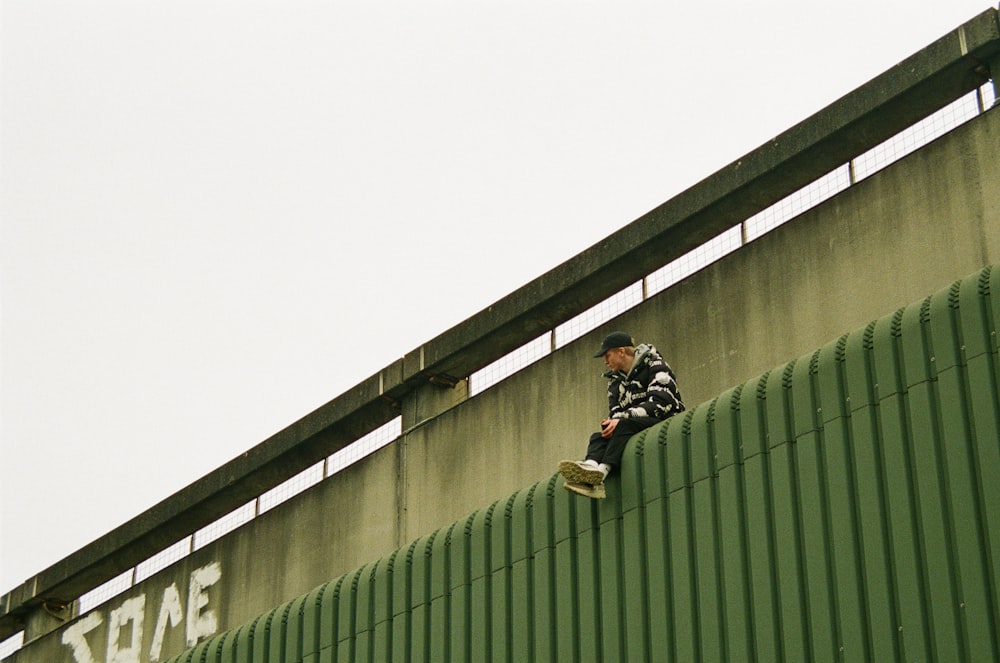 a man standing on the side of a green wall