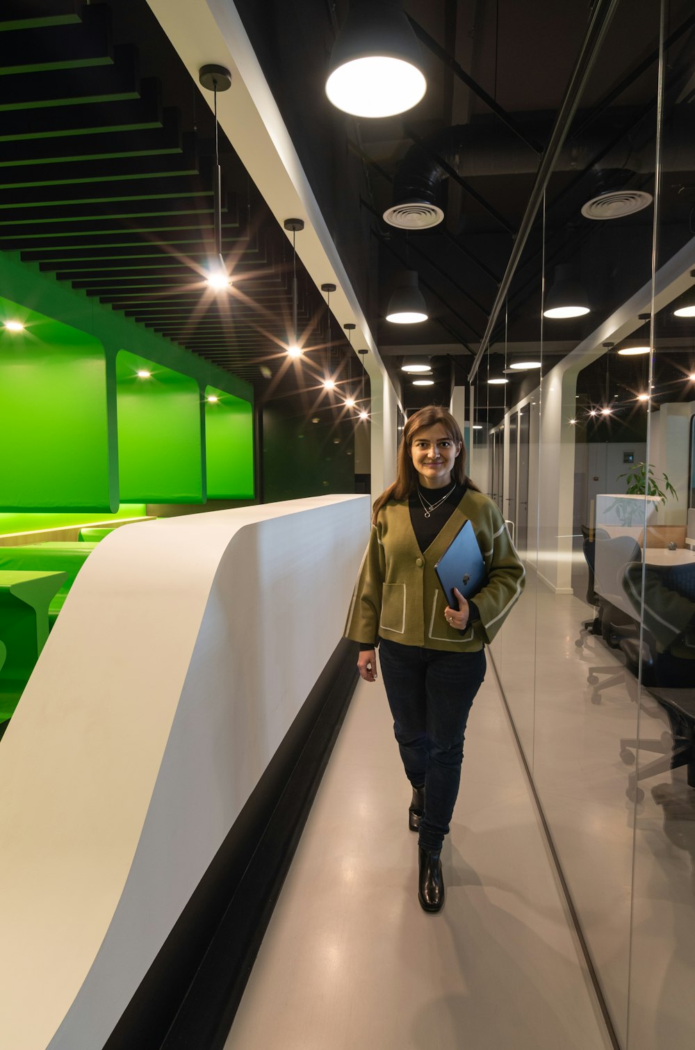 a woman walking down a hallway with a book in her hand