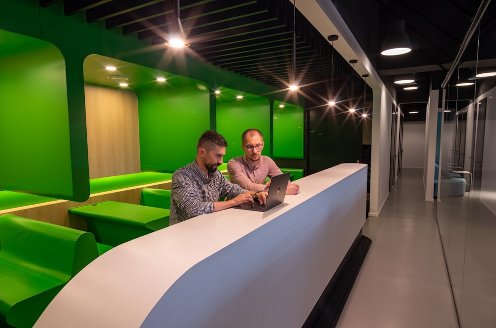 a couple of men sitting at a table with a laptop