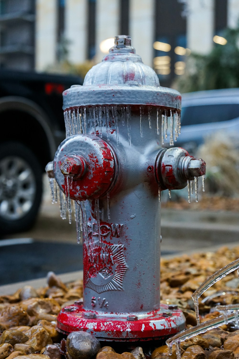 a silver and red fire hydrant sitting on the side of a road