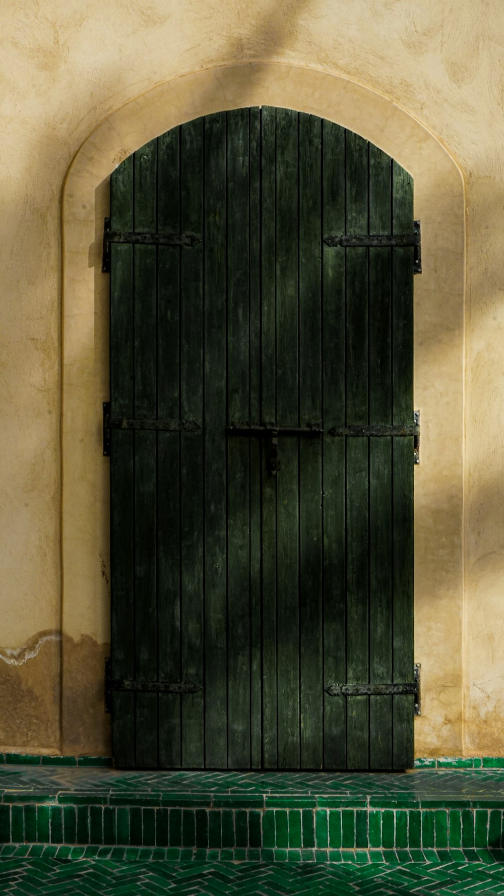 una porta verde aperta con un pavimento piastrellato verde