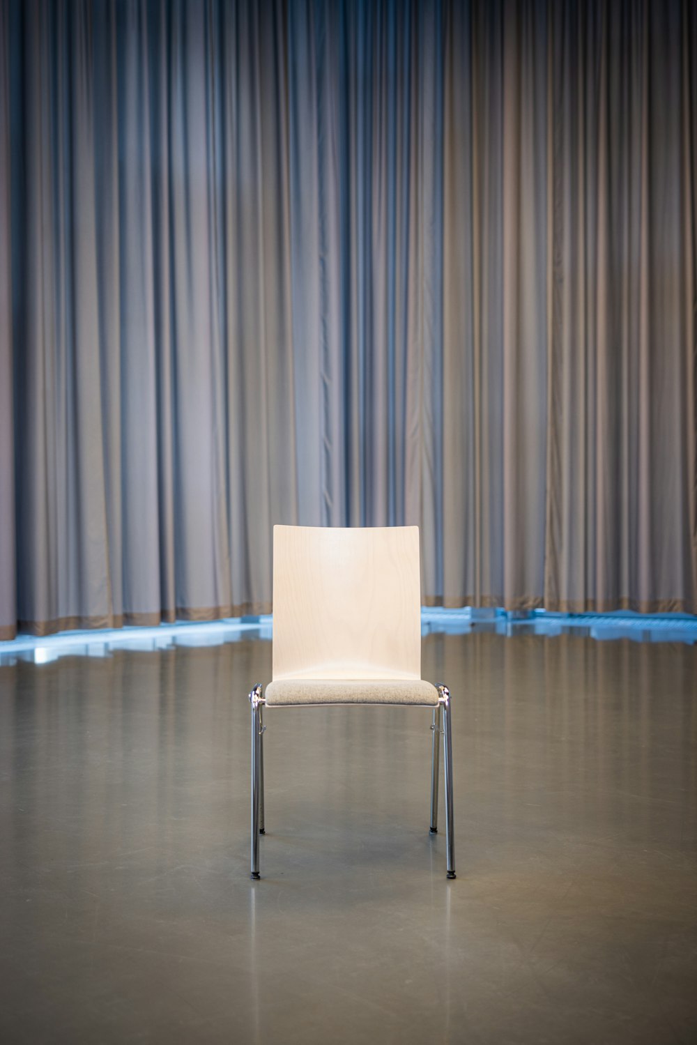 a white chair sitting in front of a curtain