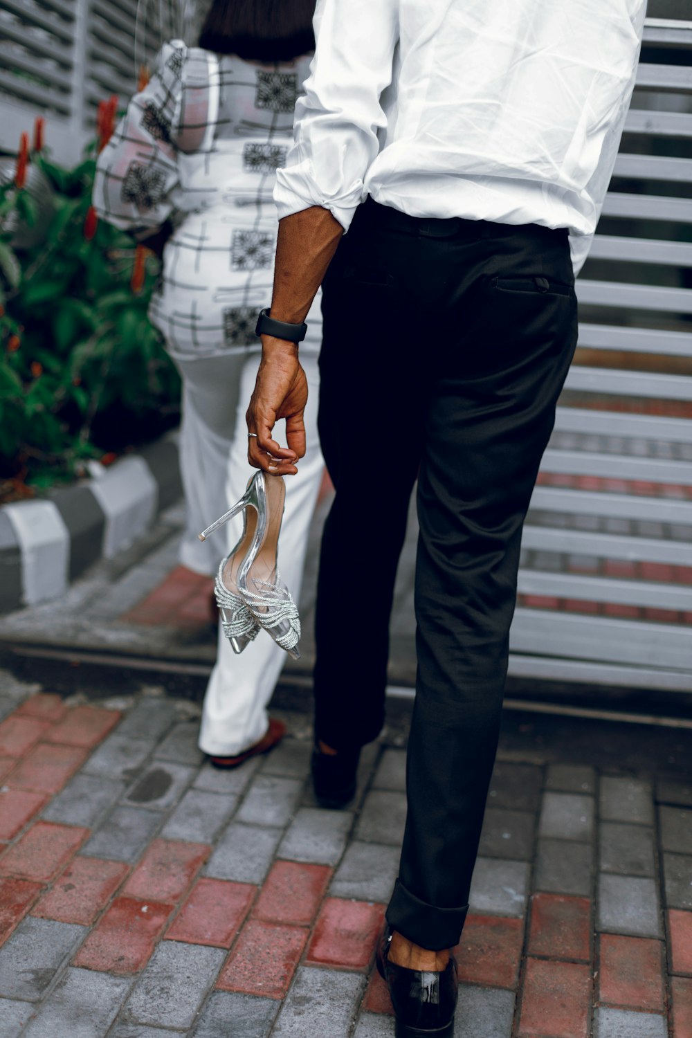 a man in white shirt and black pants holding a pair of shoes