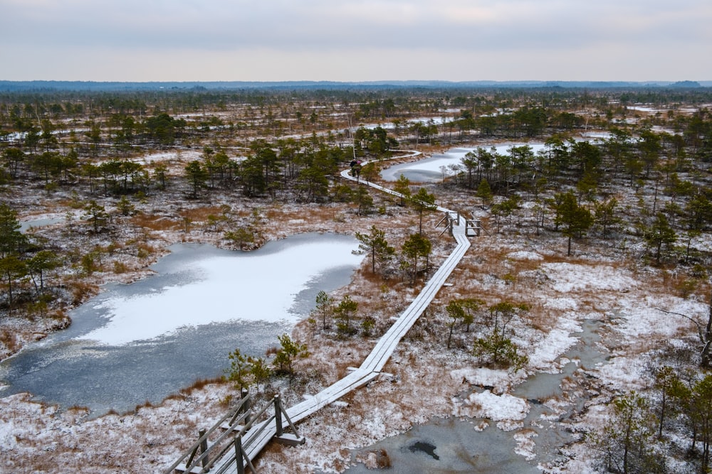 an aerial view of a snow covered area with a path leading to a pond