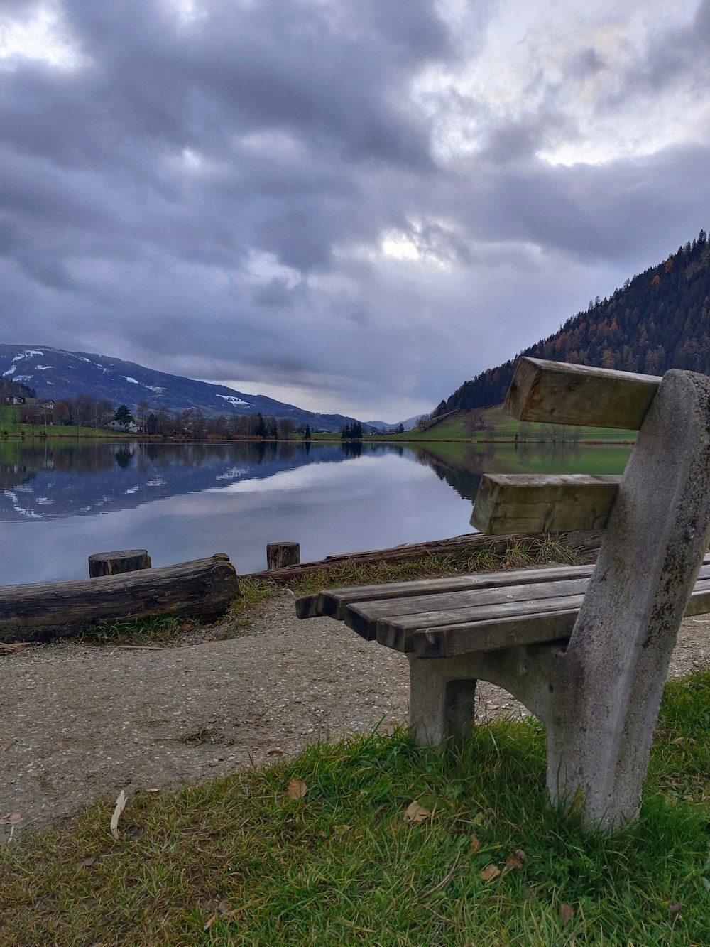a wooden bench sitting next to a lake under a cloudy sky
