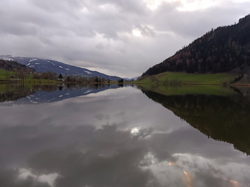 a body of water surrounded by mountains under a cloudy sky