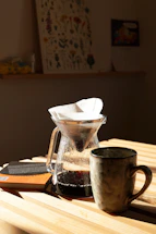 A cozy coffee setup with manual brew tools on a wooden table, inviting customers to connect.