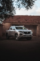 A sleek red pickup truck parked in front of a rustic finca.