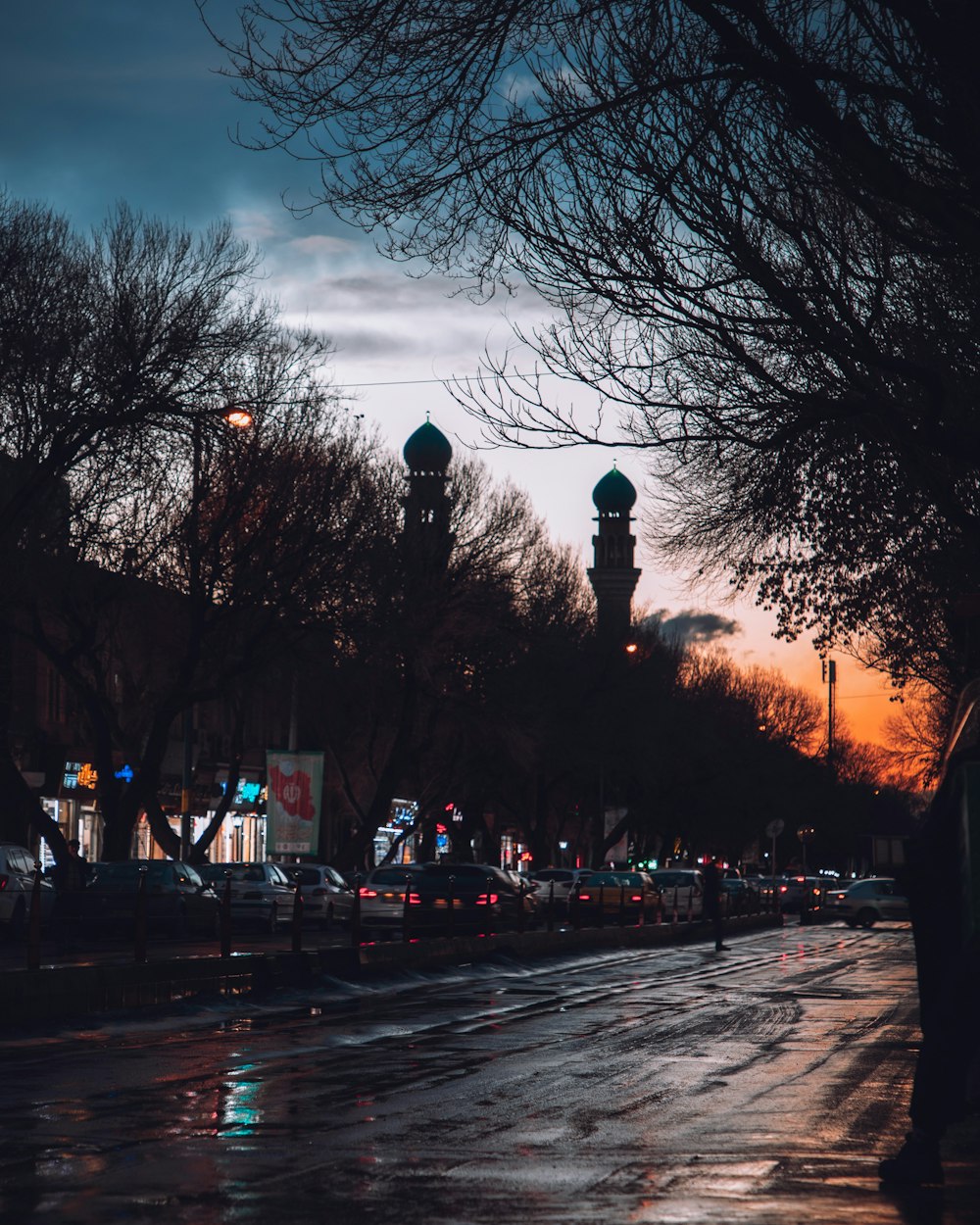 a city street at night with cars parked on the side of the road