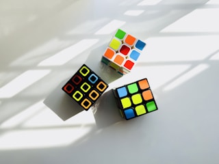 two rubik cubes sitting next to each other on a white surface