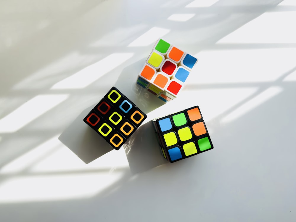 two rubik cubes sitting next to each other on a white surface