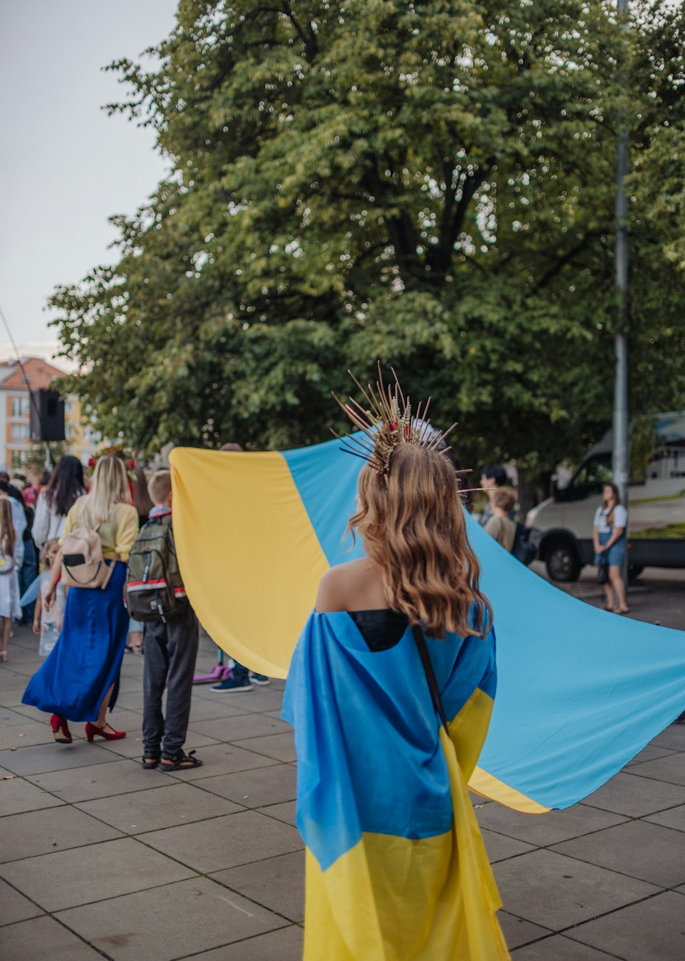 a woman in a blue and yellow dress holding a blue and yellow kite