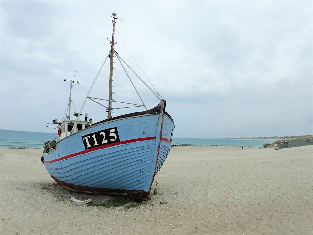 a blue boat sitting on top of a sandy beach