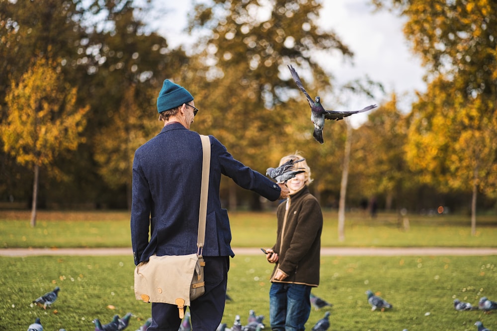 a man and a boy standing in a field with a flock of birds