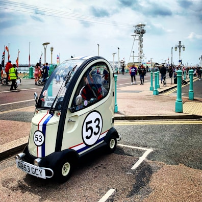 Compact red city car parked near a sunny beachside boardwalk.