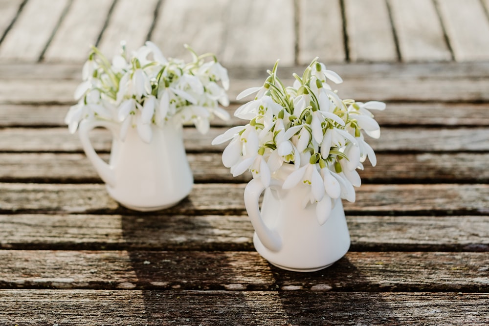 a couple of white vases filled with white flowers