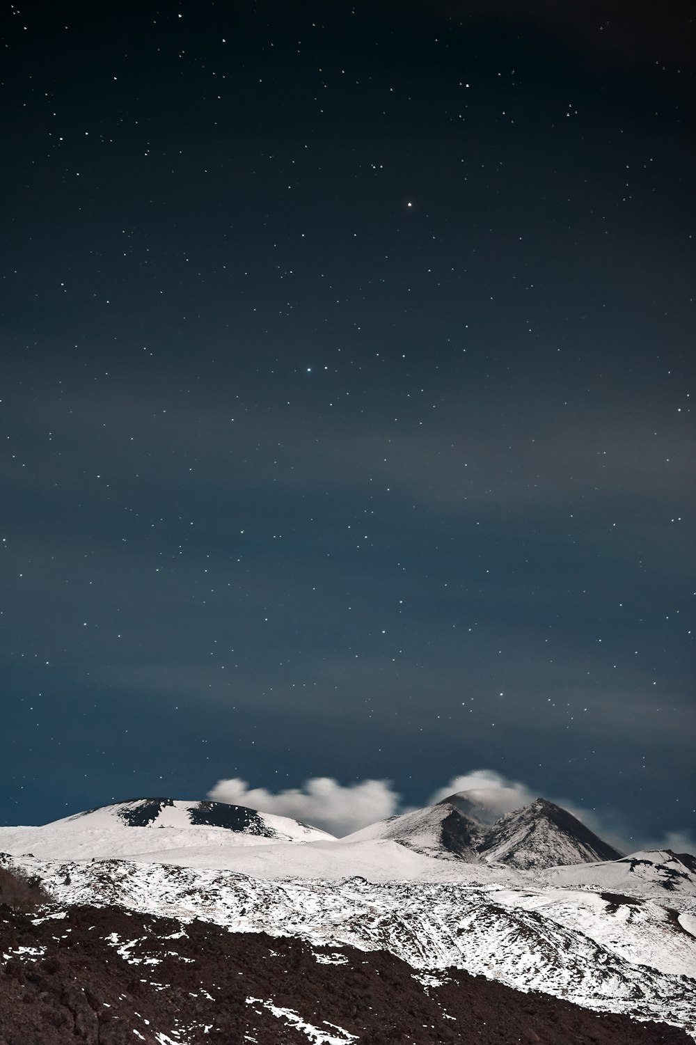 the night sky over a snowy mountain range