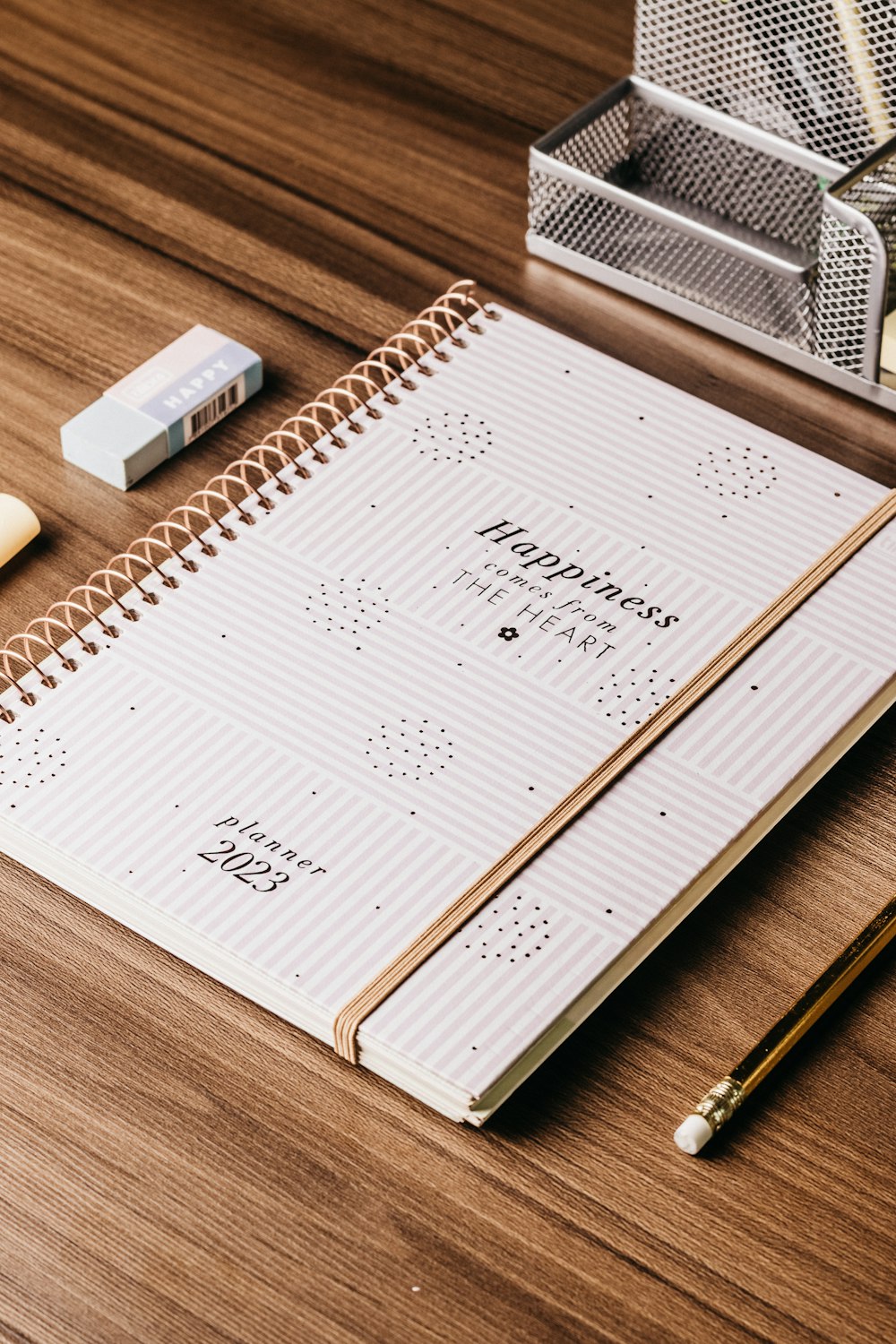 a notebook with a pen and pencil on a wooden table