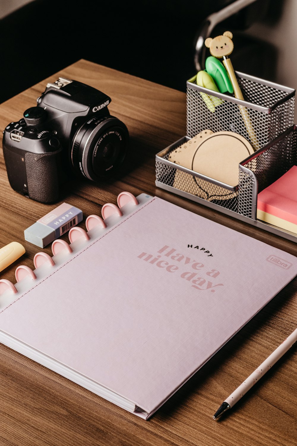 a desk with a camera, notebook, pen and pencils