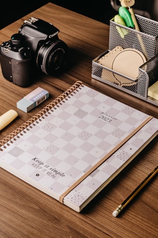 A stack of assorted office supplies on a wooden desk.