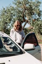 A smiling family standing beside their car on a sunny day.