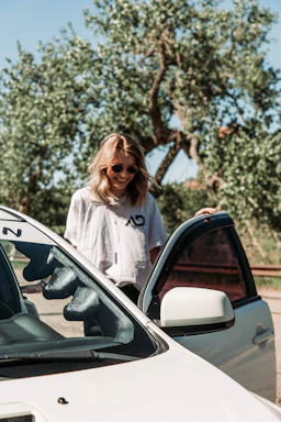 A friendly customer handing over car keys to a smiling buyer in a sunny parking lot.