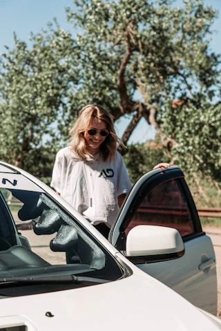 A friendly sales team member handing car keys to a smiling customer beside a shiny SUV under a bright sky.