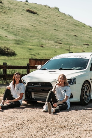 A happy couple enjoying a scenic tour in Armenia, standing next to a sleek rental car with rolling hills in the background.