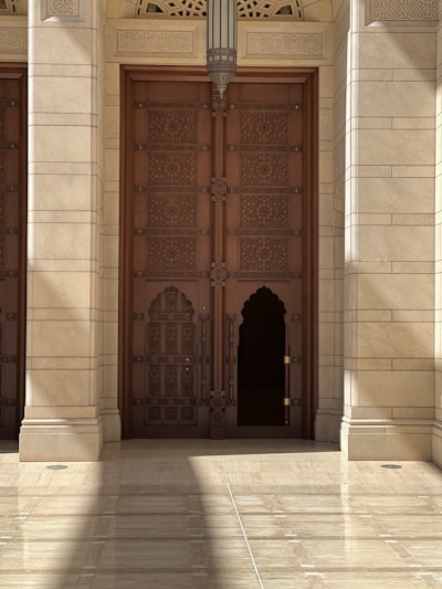 A grand wooden door with intricate carvings, standing tall in a bright, modern interior.