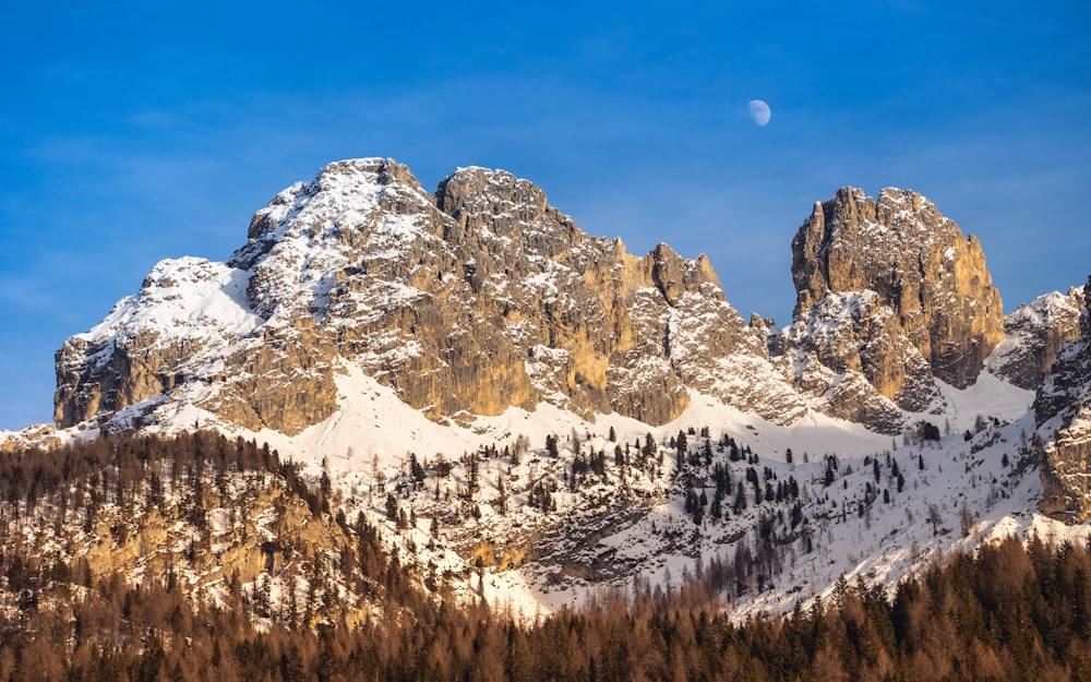 a snow covered mountain with a full moon in the sky