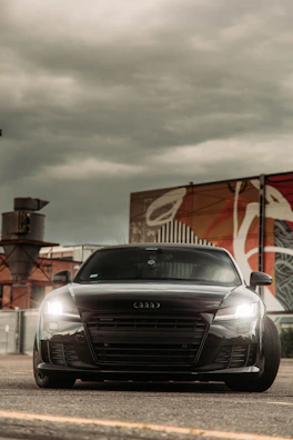 Audi RS3 in deep anthracite grey, captured on a sleek urban street at dusk.