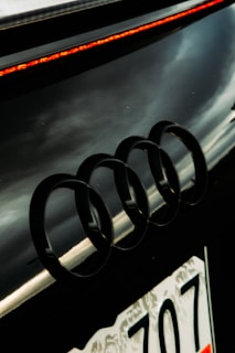 Audi four rings badge shining on a dark car hood