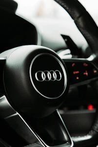 Close-up shot of a carbon fiber steering wheel cover with metallic silver accents under moody lighting.