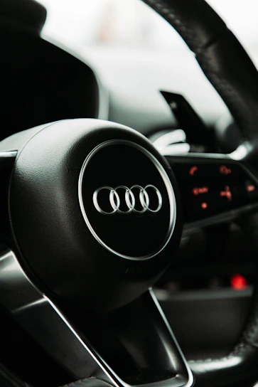 Close-up shot of a carbon fiber steering wheel cover with metallic silver accents under moody lighting.