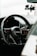 A sleek black steering wheel with the Audi logo in the center, set against a modern car interior. The dashboard displays illuminated control buttons with red backlighting. A smartphone holder is attached to the windshield.