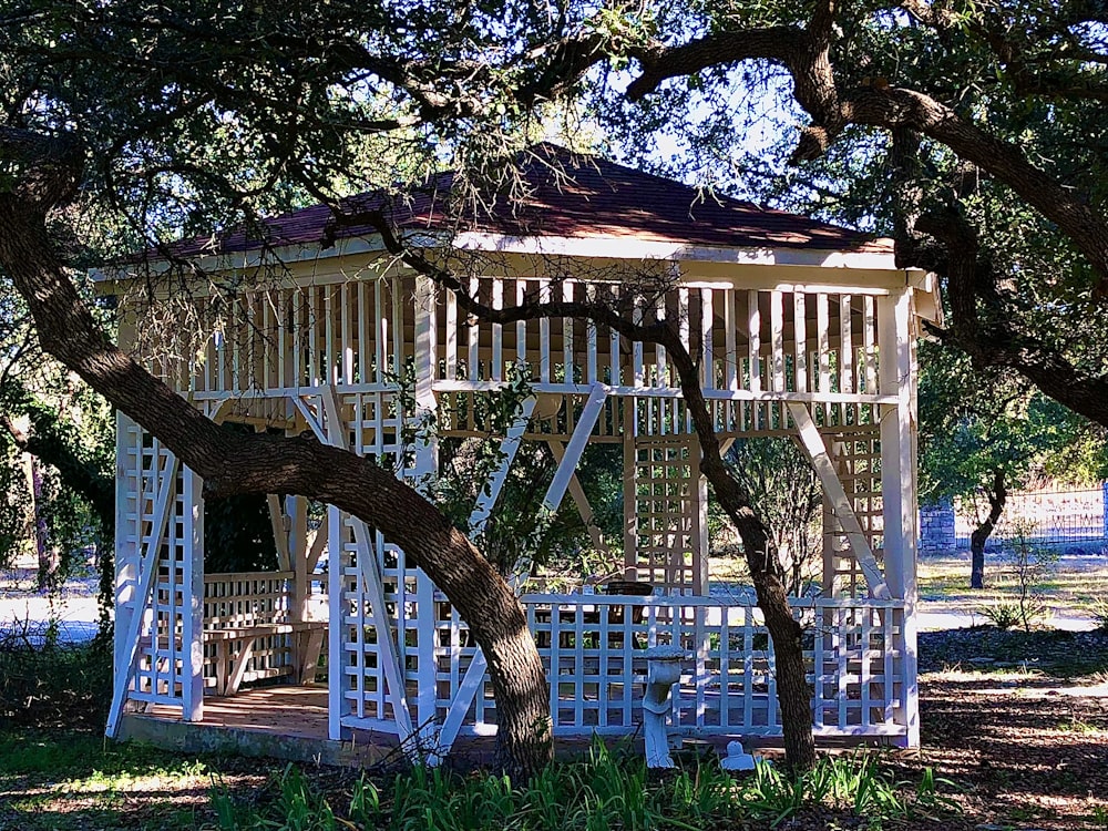 a white gazebo surrounded by trees in a park