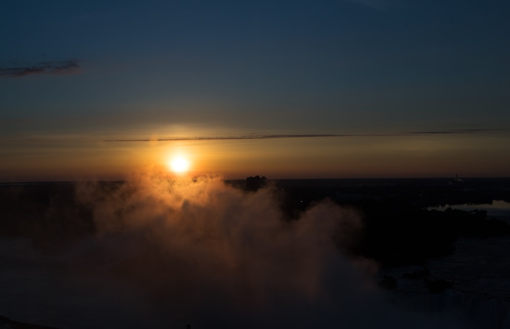 the sun is setting behind a cloud of smoke