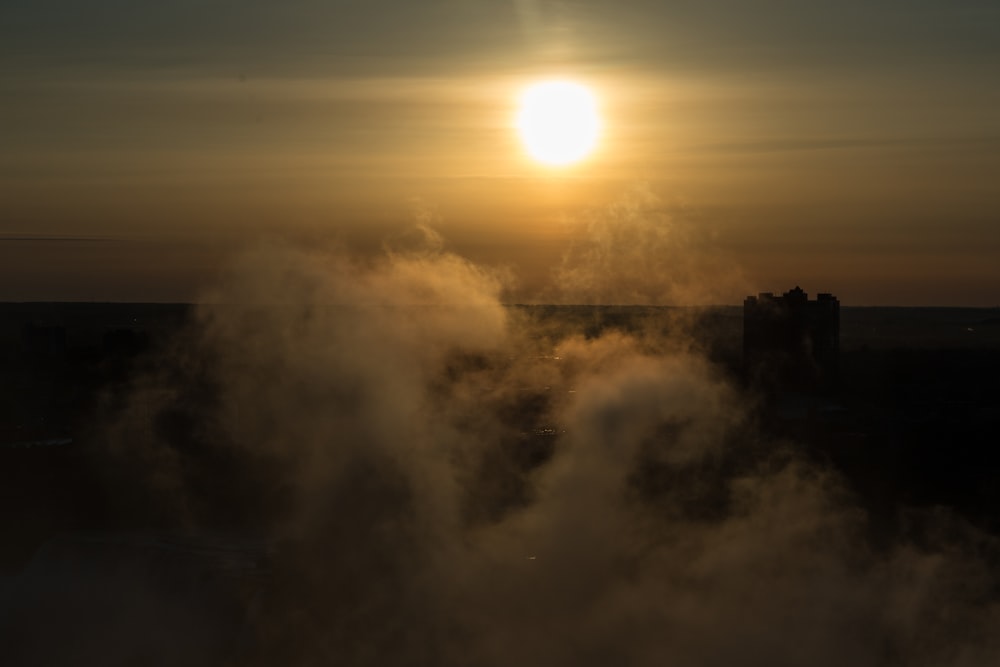 the sun is setting over a foggy city