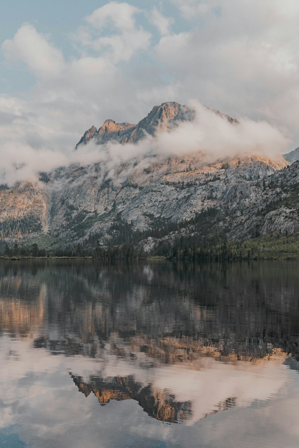 a mountain range is reflected in the still water of a lake