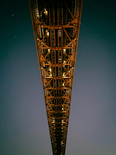Night view of a steel bridge illuminated by construction lights.