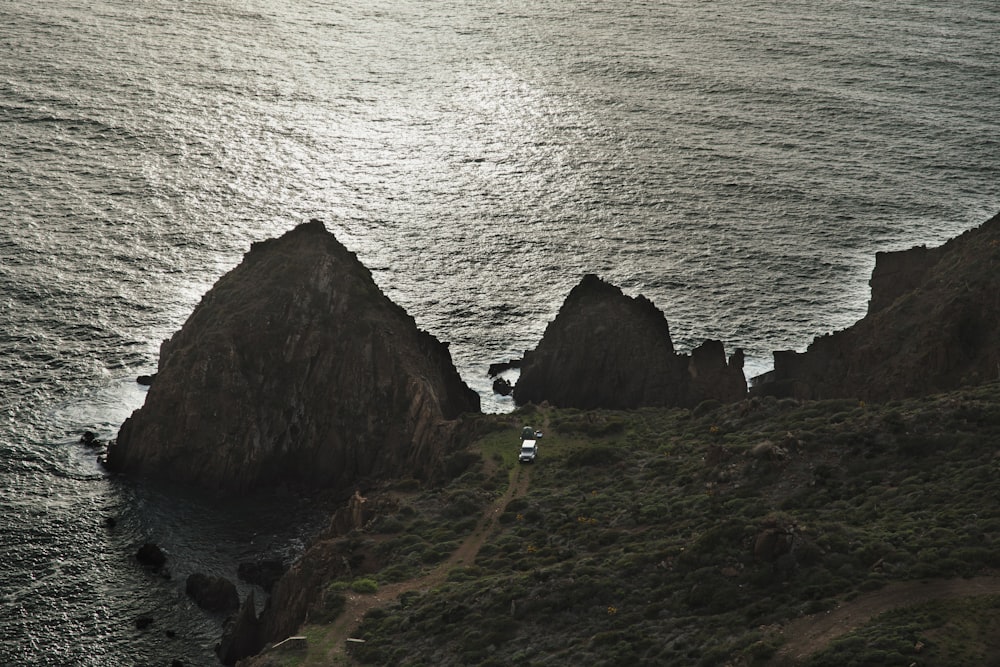 a couple of large rocks sitting on the side of a body of water