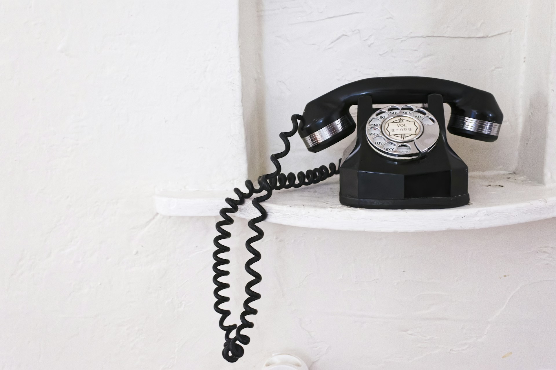 a black phone sitting on top of a white shelf