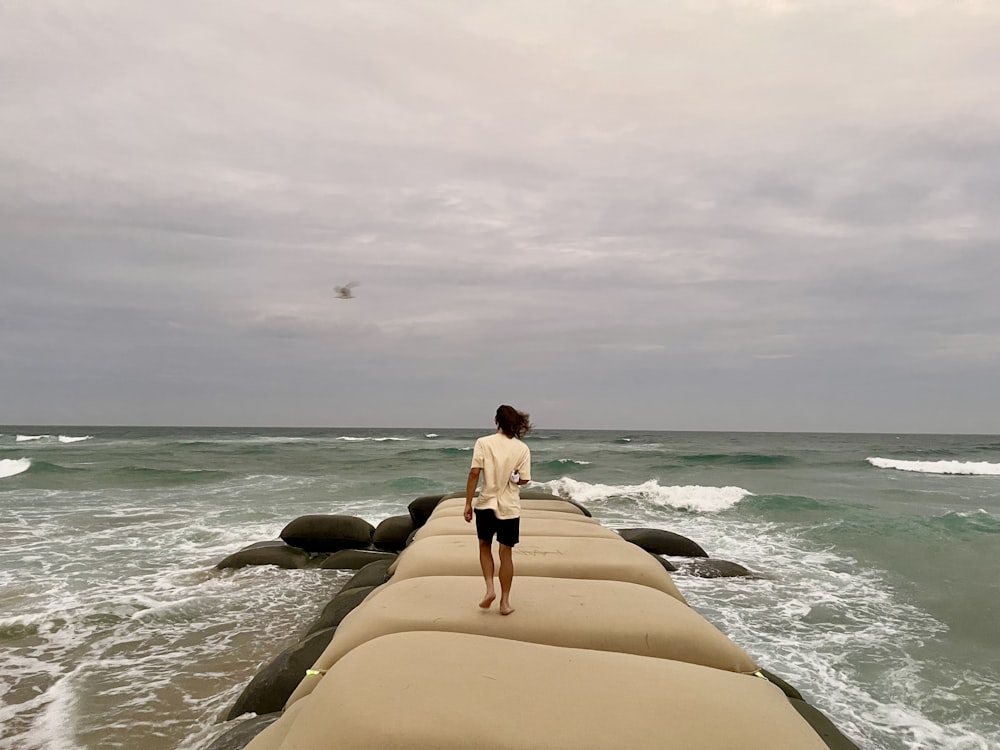 a man standing on a long pier next to the ocean