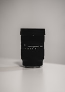 A minimalist black and white photo of a camera lens reflecting golden light.